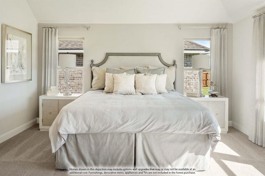 Bedroom with upholstered gray headboard, neutral bedding, two windows with curtains, and carpet flooring