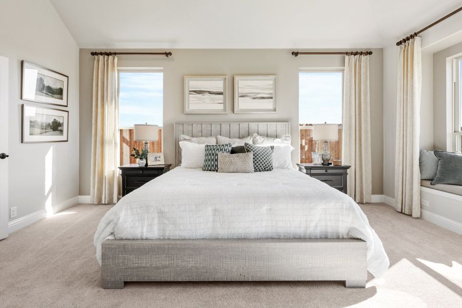 Master bedroom with king bed, gray upholstered headboard, multiple windows, and a window seat