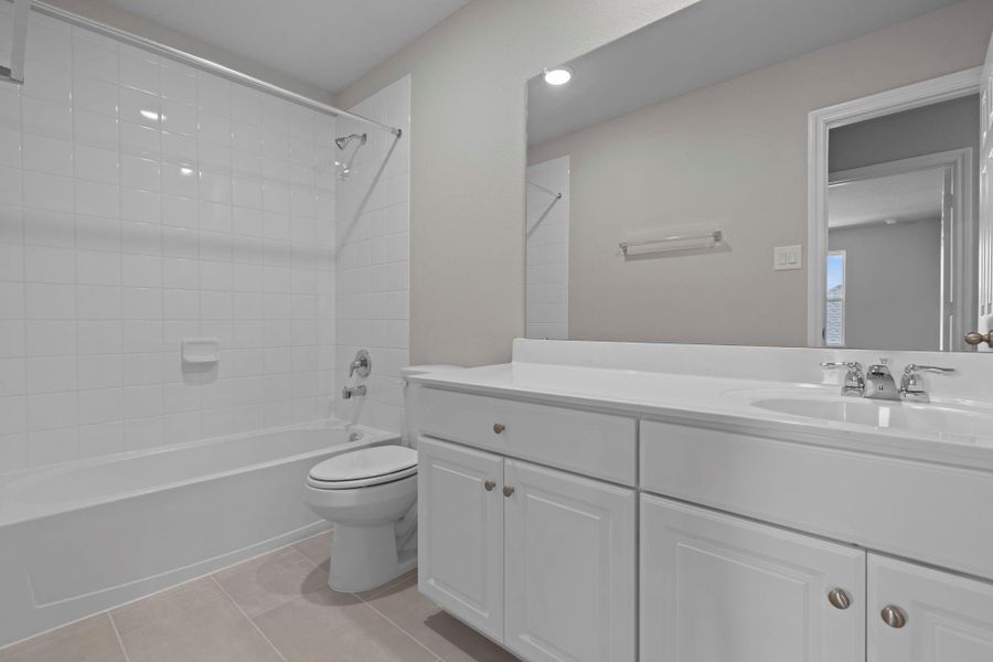 The secondary bath features tile flooring, white cabinetry and light countertops and a shower/tub combo. Perfect for accommodating any visiting family and friends.