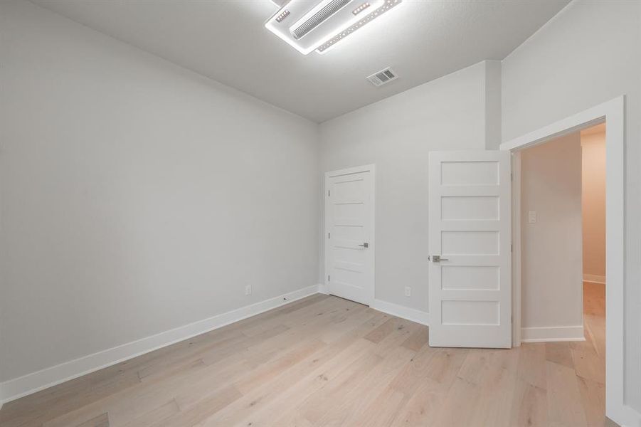 Empty room featuring cooling unit, light wood-type flooring, and lofted ceiling