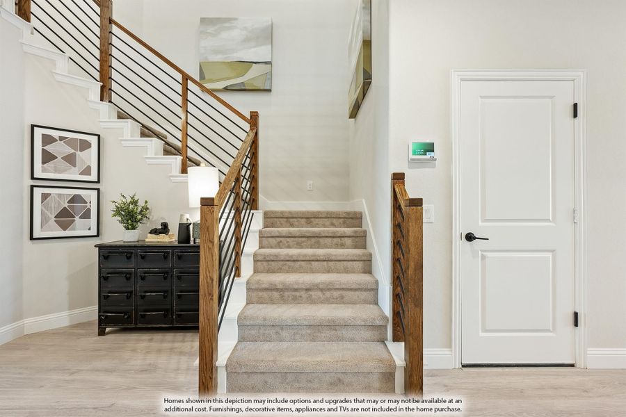 Carpeted staircase with wood and metal railing in a bright entryway with hardwood floors