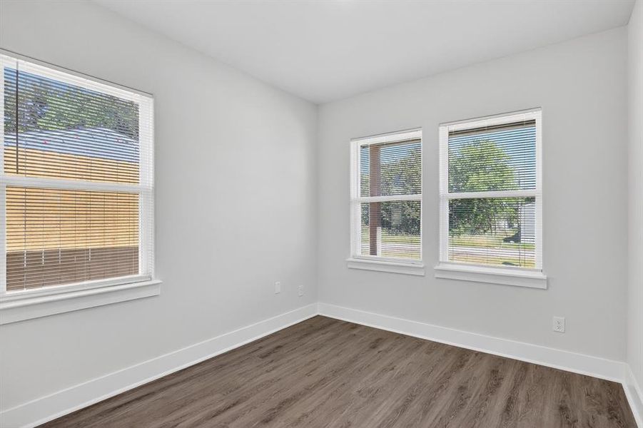 Room featuring wood-finish flooring, crisp white baseboards, and light gray walls