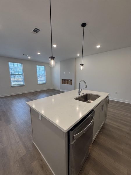 Kitchen with open floor plan, stainless steel dishwasher, dark wood-style flooring, a kitchen island with sink, and gray cabinetry