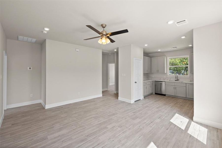 Unfurnished living room featuring light hardwood / wood-style floors, sink, and ceiling fan