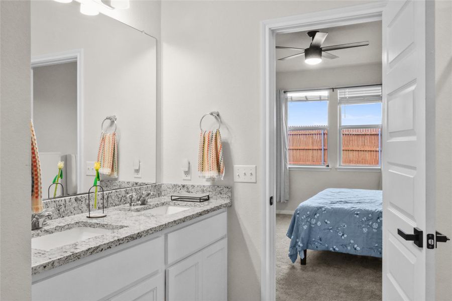 Ensuite bathroom featuring double vanity and a ceiling fan