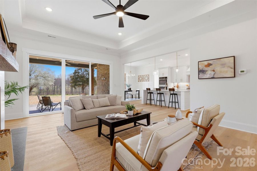 living room w/ ventless gas fireplace, tray ceiling, and 8ft sliding glass doors to the covered rear patio