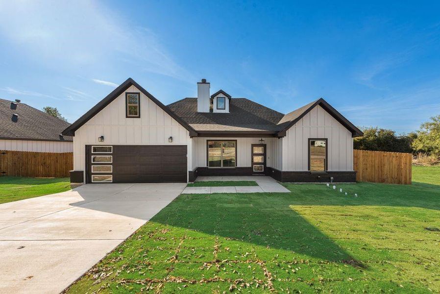 Modern farmhouse featuring a front yard and a garage