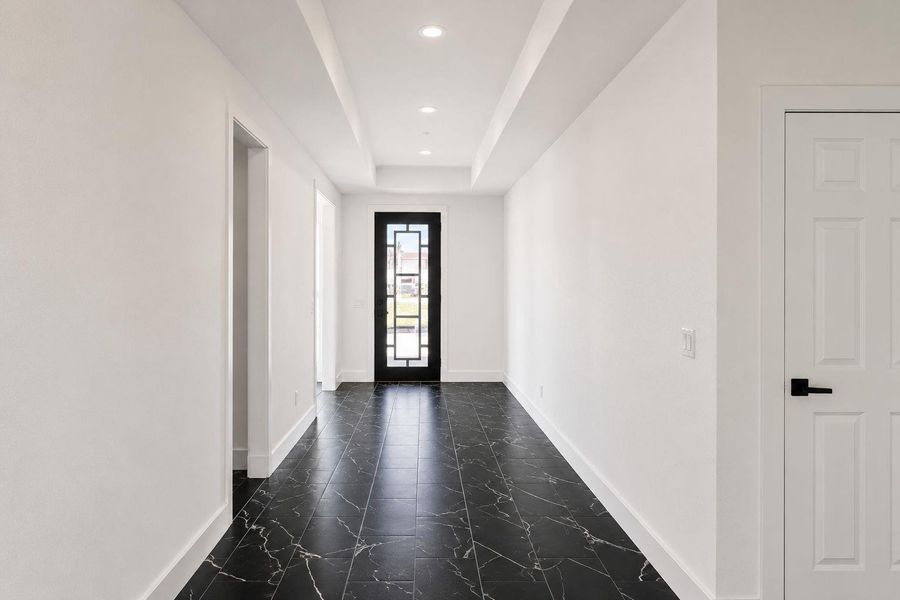 A well-lit entry hall with chic marble-look tile flooring welcomes guests.