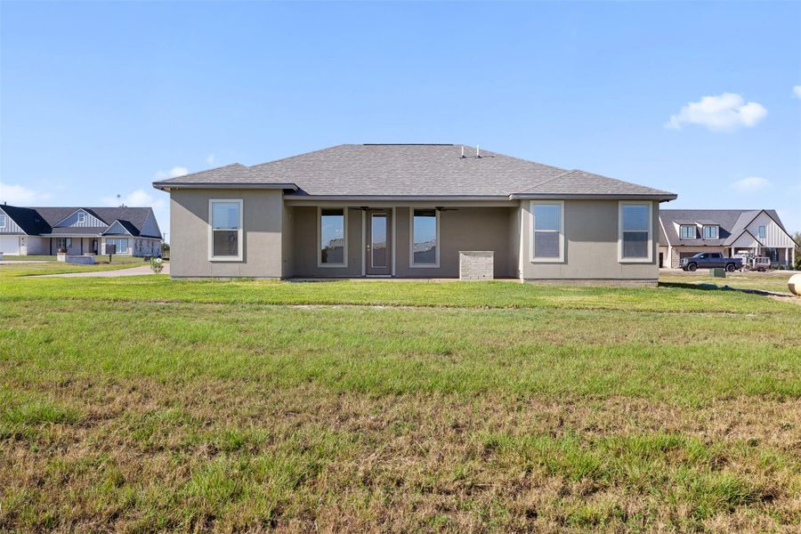 Back of house featuring a lawn, stucco siding, and a patio area