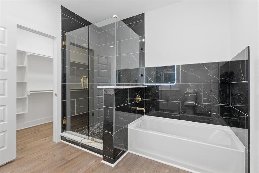 Contemporary bathroom featuring a walk-in shower with clear glass enclosure and gold-finish hardware, a built-in soaking tub, and black marble-look tile accents
