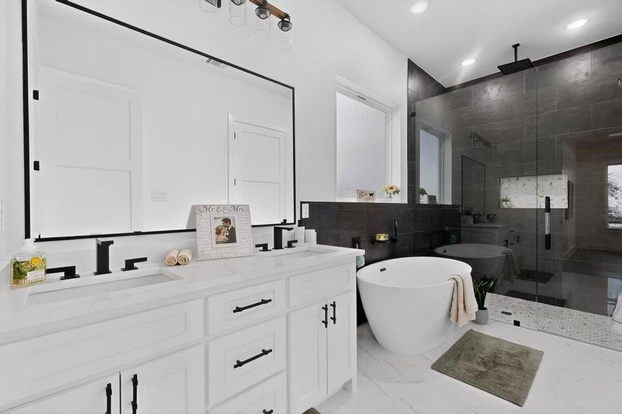 Primary Full bathroom with a freestanding bath, a shower stall, double vanity, tile walls, and light marble finish floors Primary Full bathroom with a freestanding bath, a shower stall, double vanity, tile walls, and light marble finish floors