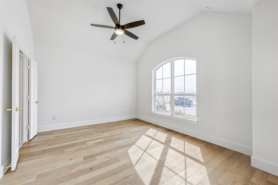 Unfurnished room featuring lofted ceiling, a ceiling fan, and light wood finished floors