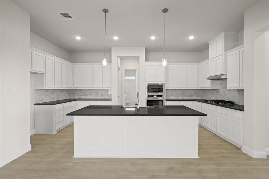 Kitchen with appliances with stainless steel finishes, dark countertops, range hood, decorative backsplash, and recessed lighting