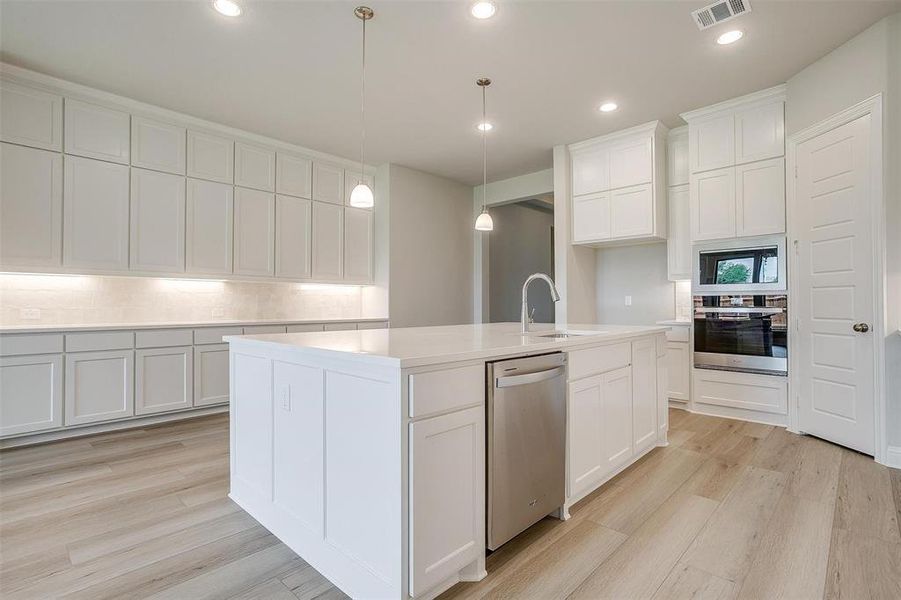 Kitchen featuring appliances with stainless steel finishes, light hardwood / wood-style flooring, white cabinets, and sink