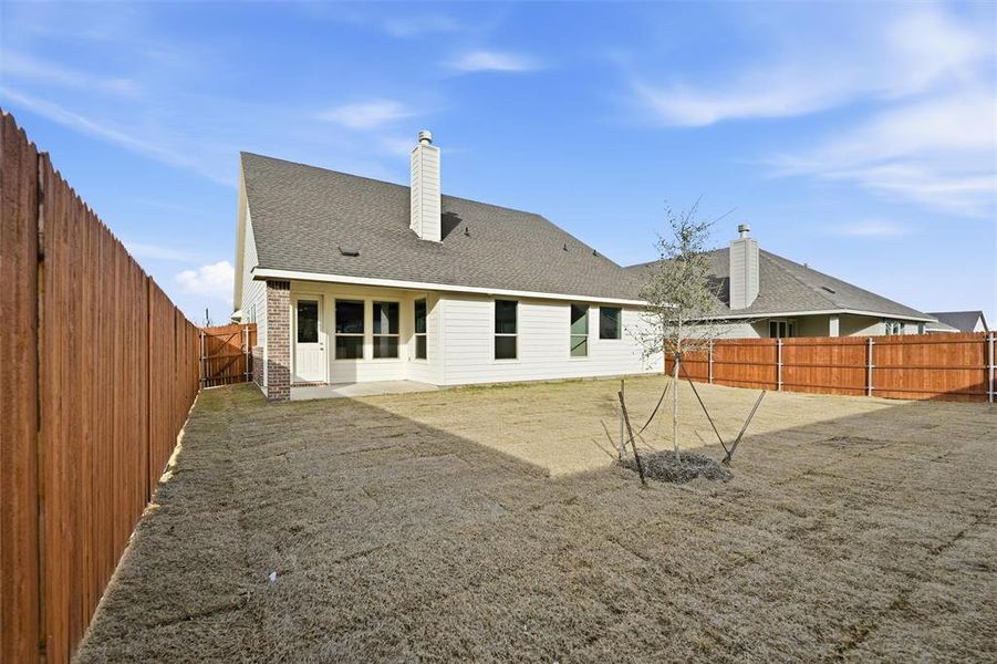 Back of house with a fenced backyard, roof with shingles, a patio, and a chimney