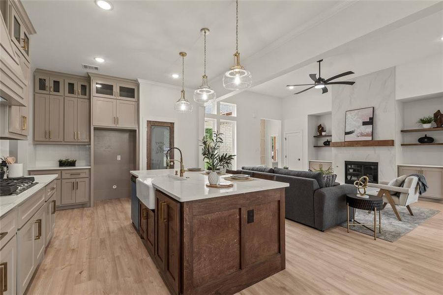 Kitchen with a sink, ornamental molding, light countertops, light wood-style floors, and a premium fireplace Kitchen with a sink, ornamental molding, light countertops, light wood-style floors, and a premium fireplace
