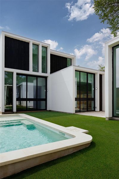 Rear view of house featuring a lawn, a patio area, and an outdoor pool