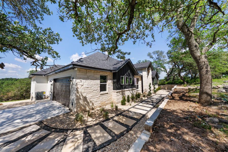 Crafted with elegant stone and modern accents, this home boasts a thoughtful pathway leading to its entrance.