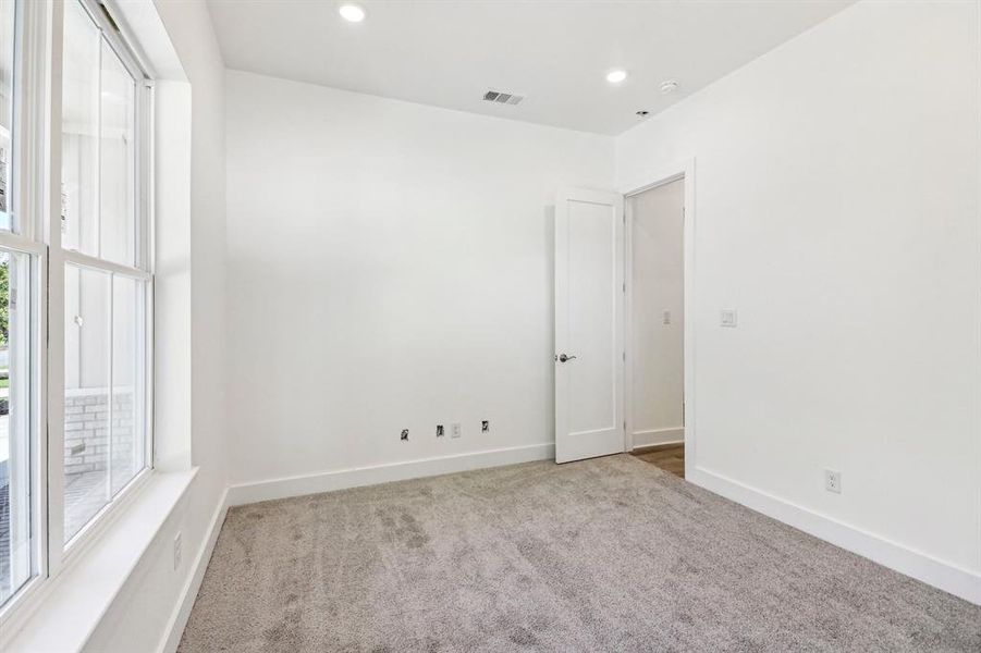 Empty room with light carpet and recessed lighting