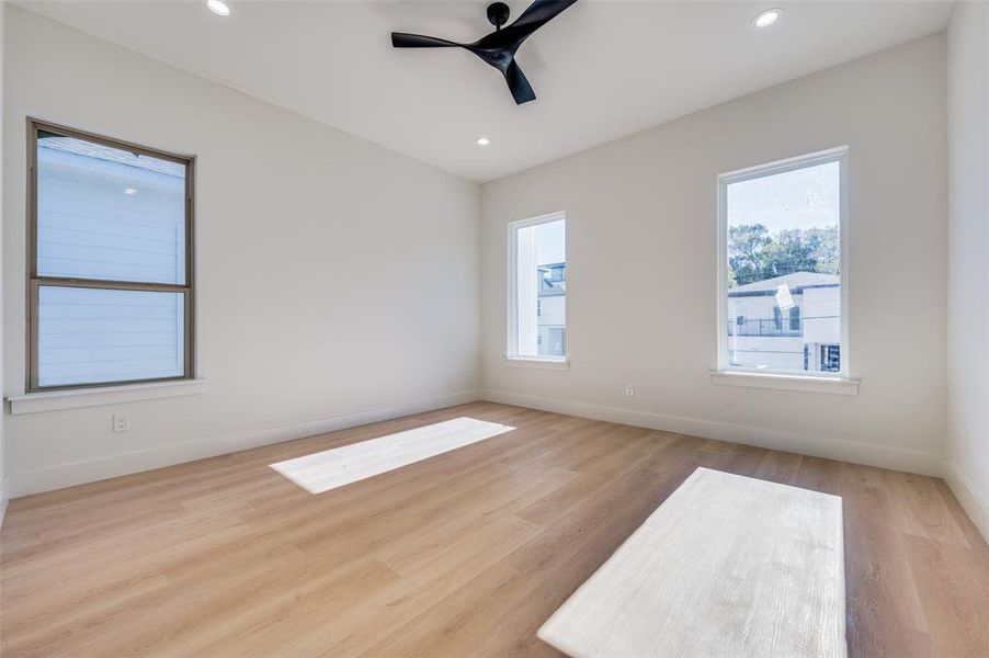 Empty room featuring ceiling fan, light wood-type flooring, and a wealth of natural light