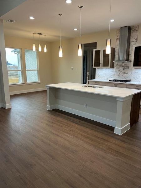 Kitchen featuring decorative light fixtures, extractor fan, a kitchen island with sink, and sink