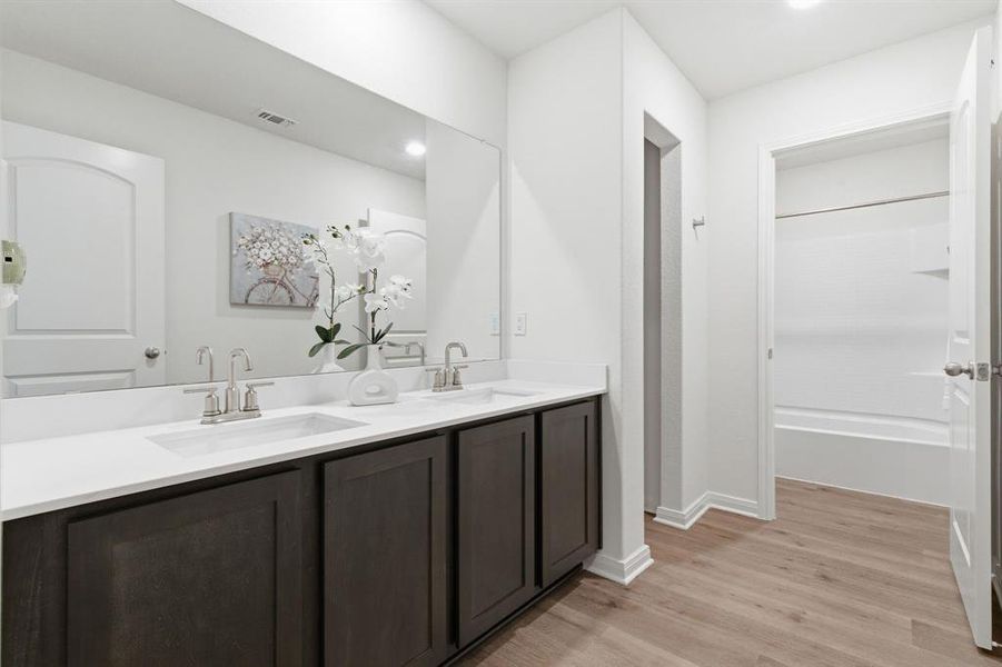 Bathroom featuring a double vanity with dark wood cabinetry, white countertops, and brushed nickel faucets