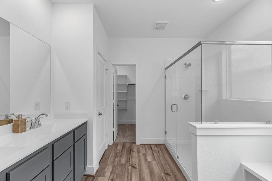 This additional view of your primary bathroom features tile flooring, fresh paint, walk-in shower, a separate garden tub, and a large walk-in closet.