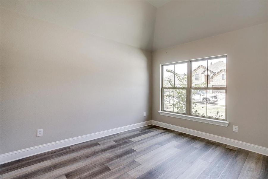 Unfurnished room with wood-type flooring and high vaulted ceiling