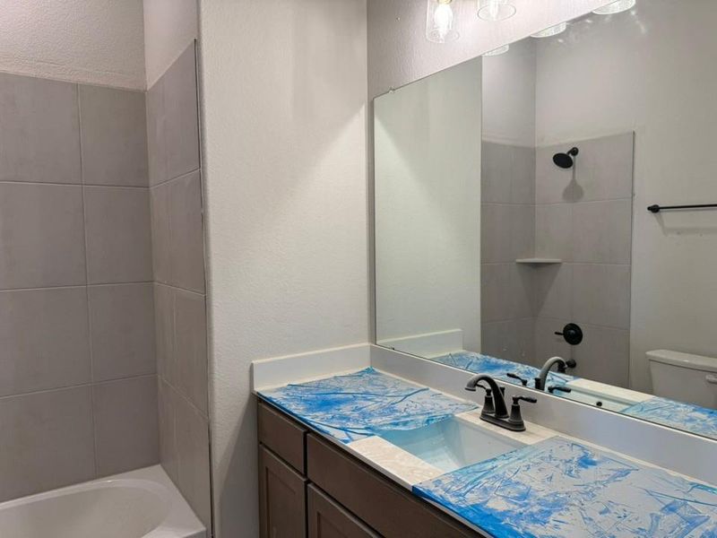 Full bath with a textured wall, shower / washtub combination, and vanity