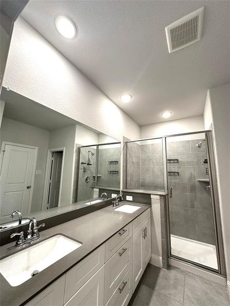 Bathroom with vanity, a textured ceiling, a shower with shower door, and tile patterned flooring