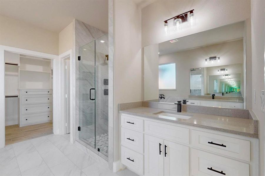 Full bath with a walk in closet, vanity, marble finish floor, and a marble finish shower