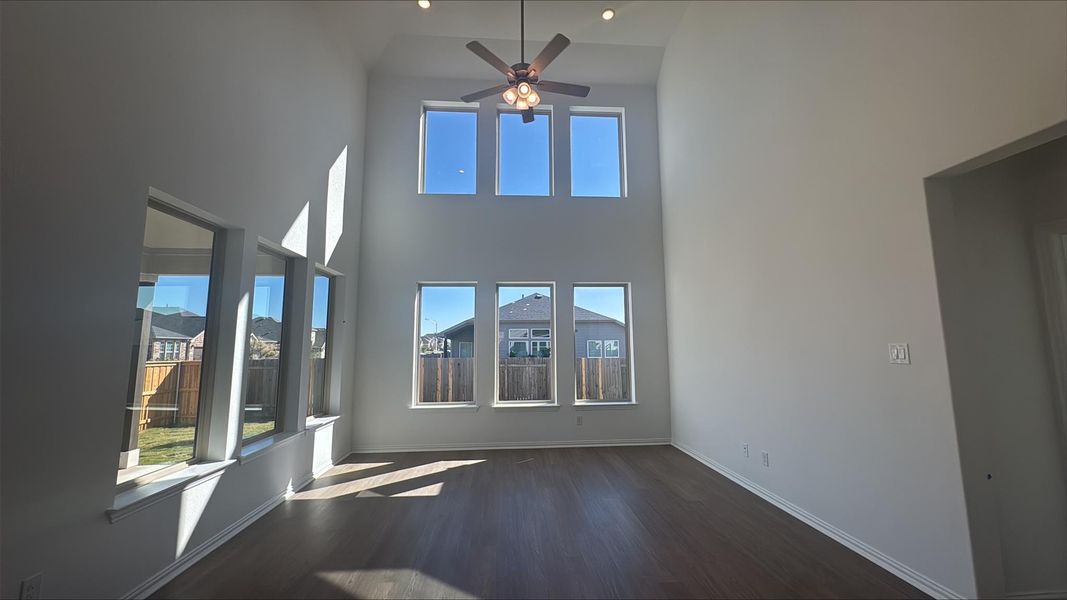 Unfurnished living room with dark wood-style floors, a high ceiling, and ceiling fan