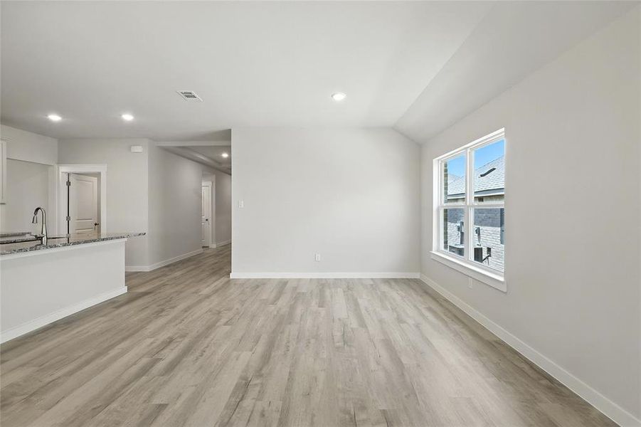 Unfurnished living room featuring light wood-type flooring, recessed lighting, and lofted ceiling