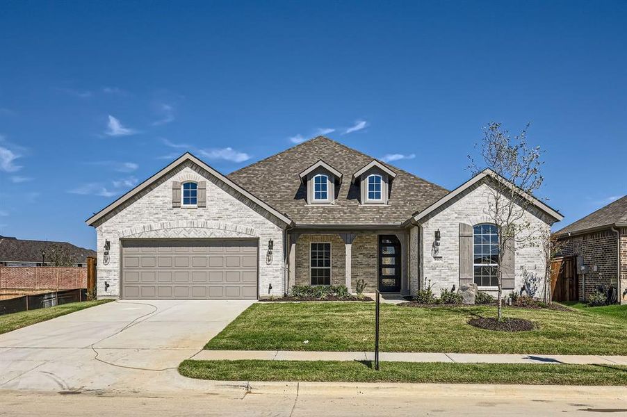 French country home with a garage and a front lawn