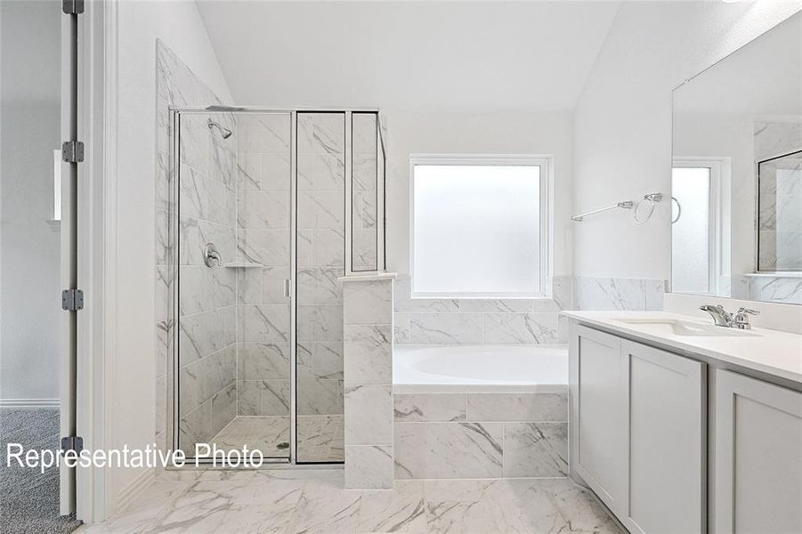Spacious bathroom featuring a glass-enclosed shower with tile surround, a built-in garden tub, and a vanity with an integrated sink and mirror