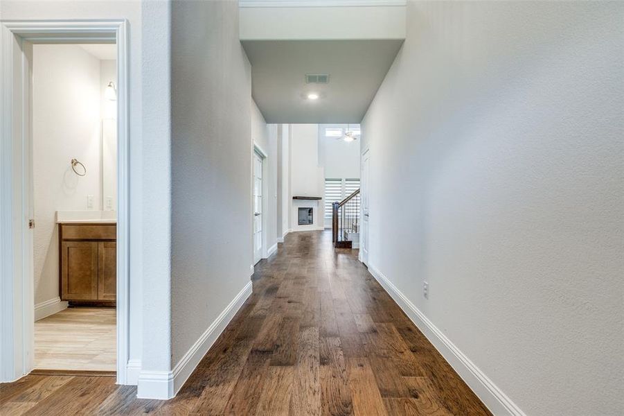 Corridor with wood finished floors, stairway, and baseboards