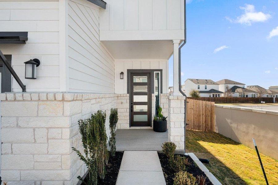Modern exterior featuring white horizontal siding, a stone veneer foundation, and a covered entryway