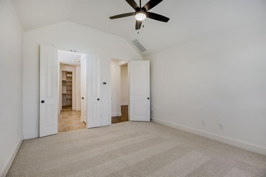 Spacious interior room with vaulted ceiling and a dark-toned ceiling fan