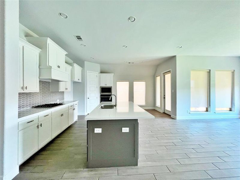 Kitchen with white cabinetry, an island with sink, backsplash, gray cabinetry, and recessed lighting Kitchen with white cabinetry, an island with sink, backsplash, gray cabinetry, and recessed lighting