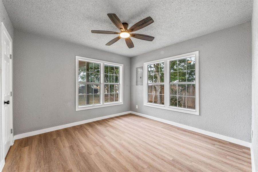Unfurnished room with a textured wall, light wood-style floors, a textured ceiling, and ceiling fan Unfurnished room with a textured wall, light wood-style floors, a textured ceiling, and ceiling fan