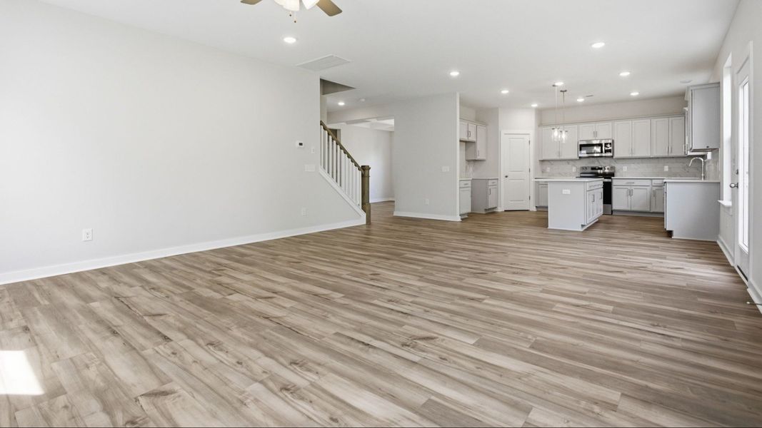 First floor with hard surface flooring, windows, nearby staircase, and view into the kitchen First floor with hard surface flooring, windows, nearby staircase, and view into the kitchen