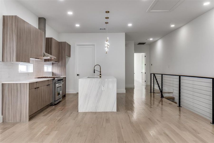 Kitchen with high end range, modern cabinets, wall chimney exhaust hood, light countertops, and recessed lighting