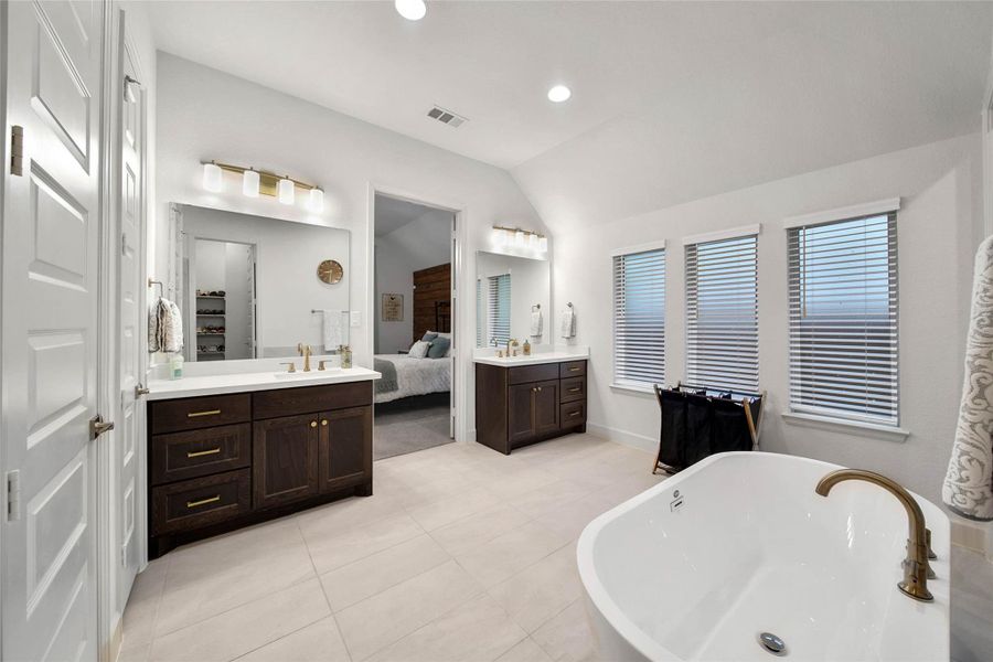Filled with natural light, this spa-like bath features dual vanities, a deep soaking tub, & a large separate shower.