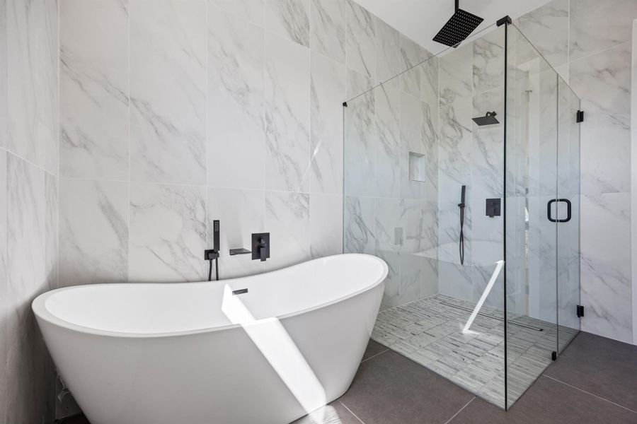 Bathroom with tile walls, a marble finish shower, a freestanding bath, and tile patterned floors