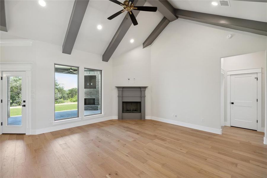 Unfurnished living room featuring beam ceiling, light wood-type flooring, and ceiling fan