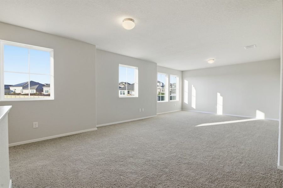 Image of a recreation room with light grey walls, tan carpeting, windows and white trim