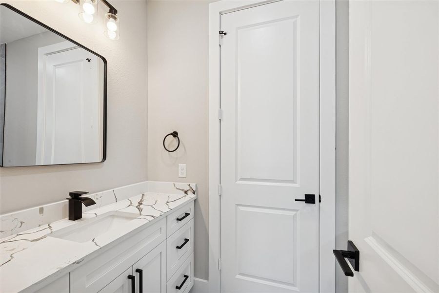 Stylish secondary bathroom featuring modern fixtures, sleek cabinetry, and elegant marble-look countertops.