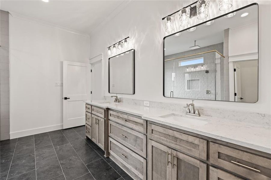 Bathroom featuring a dual vanity with light wood-finish cabinetry, white countertops, and undermount sinks
