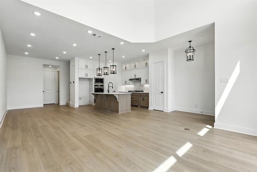 Kitchen with a breakfast bar, open floor plan, a kitchen island with sink, white cabinets, and recessed lighting Kitchen with a breakfast bar, open floor plan, a kitchen island with sink, white cabinets, and recessed lighting