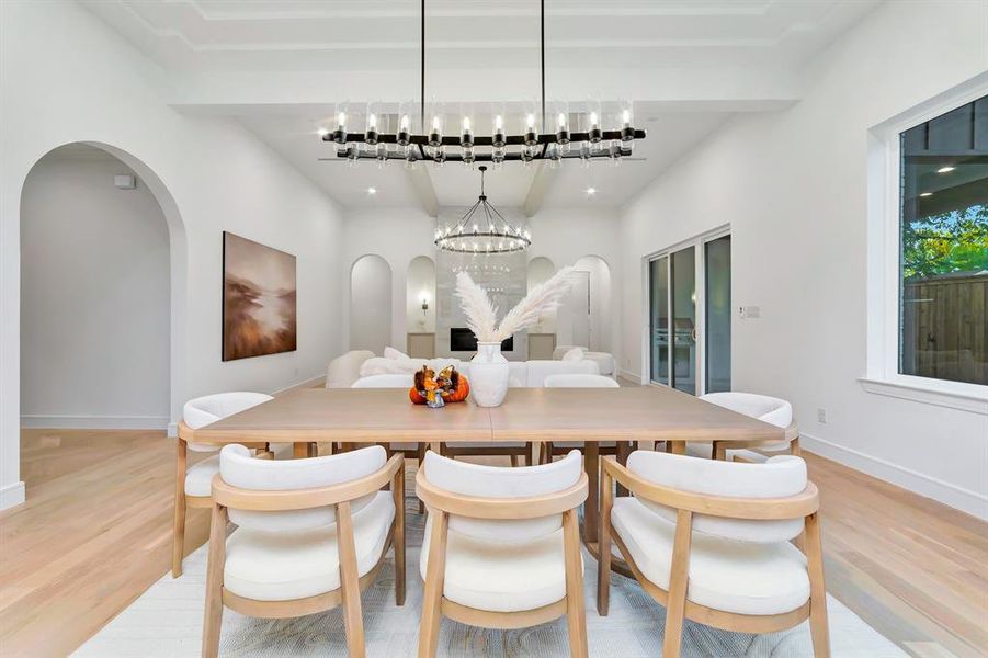 Dining room featuring arched walkways, light wood finished floors, and a chandelier Dining room featuring arched walkways, light wood finished floors, and a chandelier